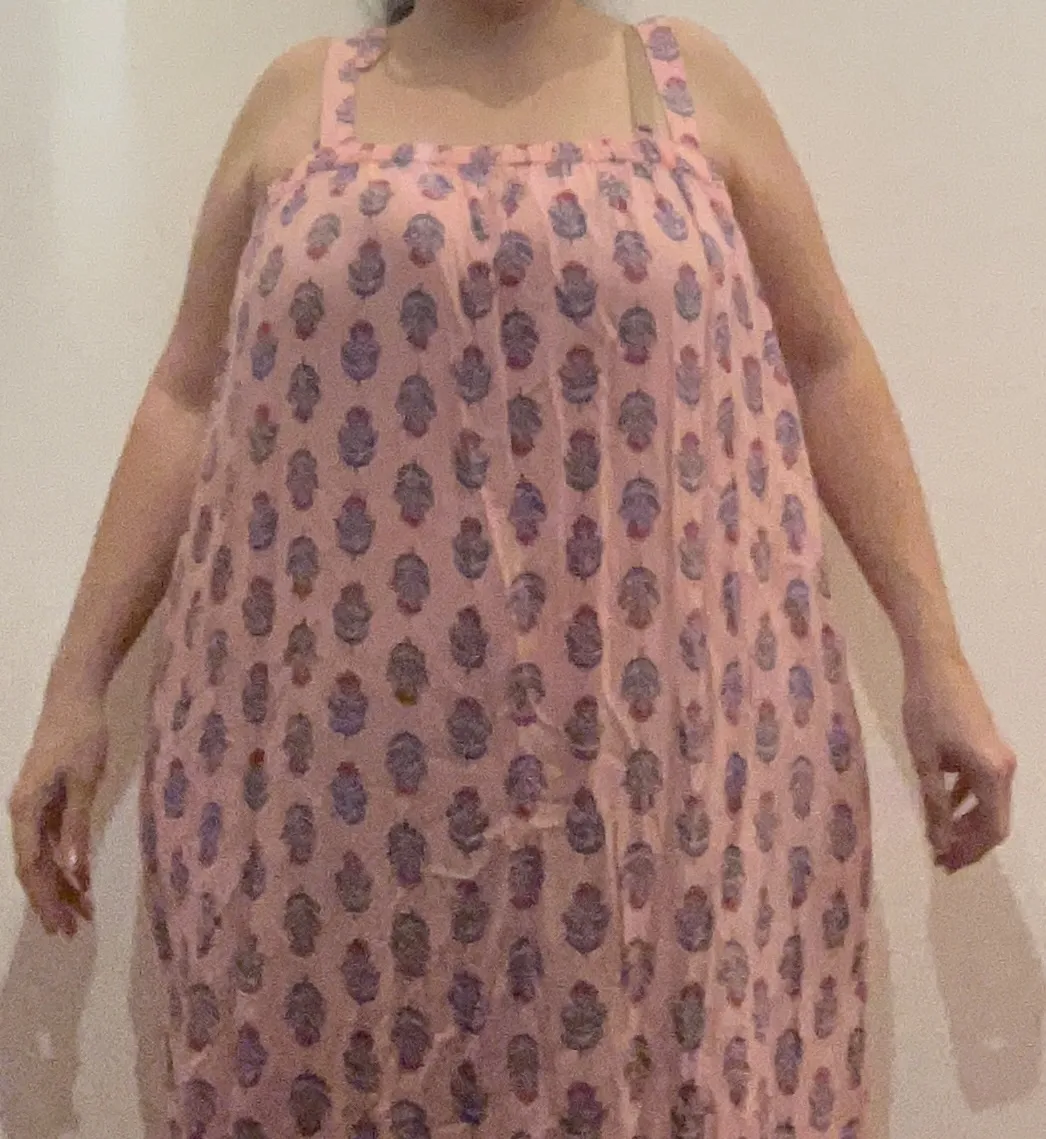 Vestido largo rosa con estampa floral de flores y hojas en tonos azules y rojos. Breteles finos y escote cuadrado. Ideal para un look fresco y cómodo.