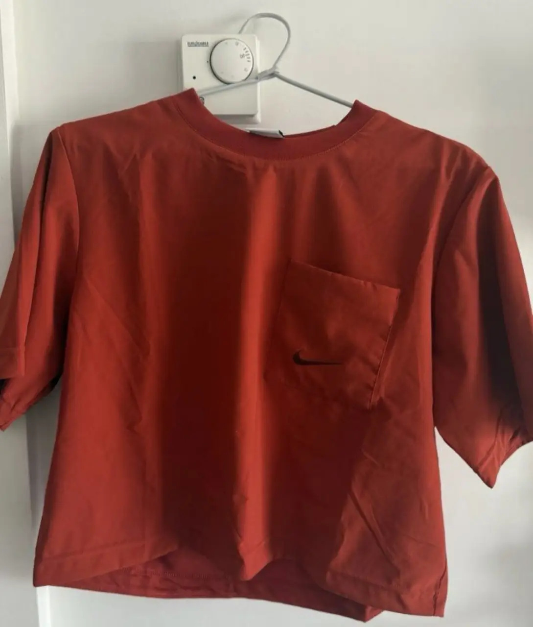 Remera Nike color bordo tierra, con bolsillo y logo bordado. Talle XS pero queda como un S, ideal para un look deportivo y casual.
