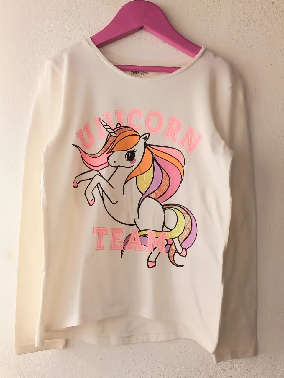 Remera blanca de manga larga con estampa de unicornio y la frase "UNICORN TEAM" en la parte delantera. La estampa es multicolor con detalles brillantes.

Medidas. De axila a axila: 34 cm, largo de manga: 48 cm, largo total: 49 cm