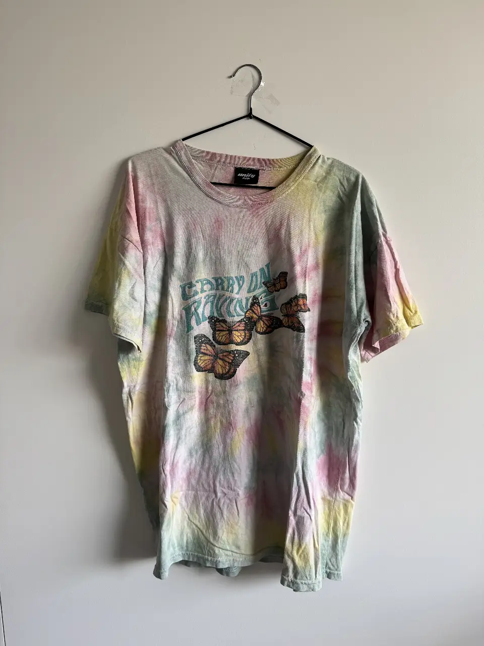 Remera tie dye con estampado de mariposas y la frase "Carry on Raving" en el frente. Marca Unity Mob. Super canchera, corte overzised🦄💘Tiene 2 manchas muy chicas, una en el frente y otra detrás (ver últimas dos fotos), casi ni se nota. Medidas: ancho 56cm, largo 74cm. 