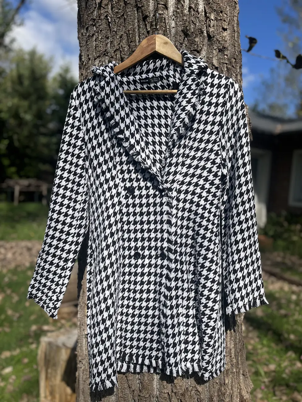 Elegante blazer largo con estampado de pata de gallo en blanco y negro. Ideal para un look sofisticado y moderno. Confeccionado con un tejido de calidad, este blazer es perfecto para cualquier ocasión.