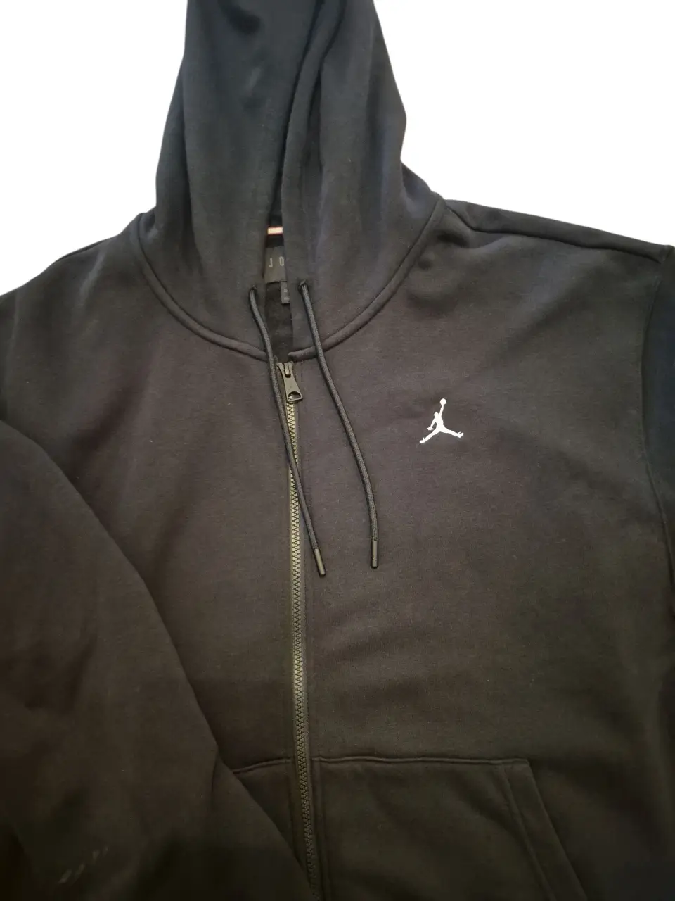 Buzo con cierre negro de hombre, con capucha y el logo de la marca Jordan bordado en blanco. Ideal para un look casual y deportivo.