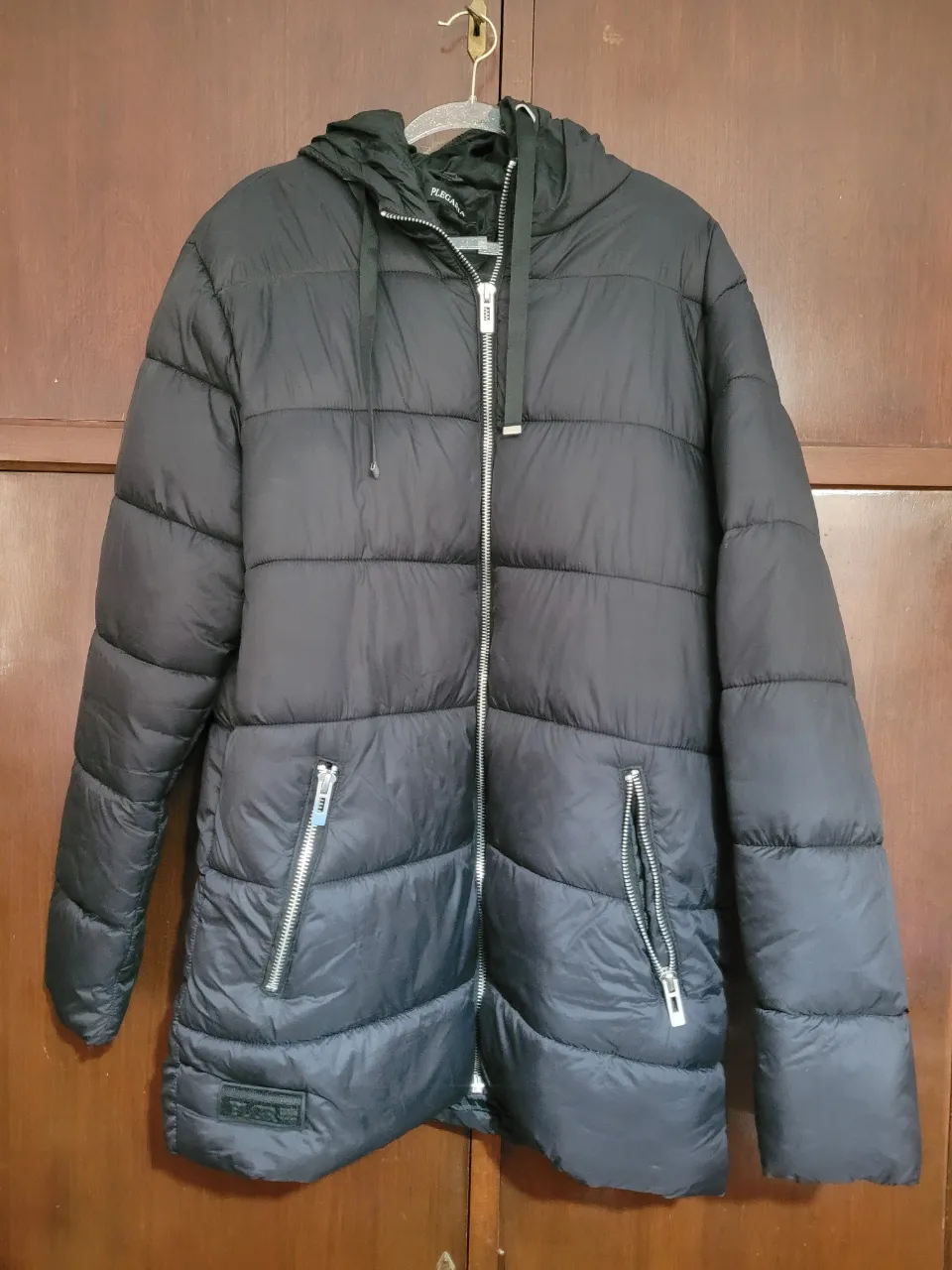 Campera de pluma negra con capucha, cierre frontal y bolsillos con cierre. Talle XXL.