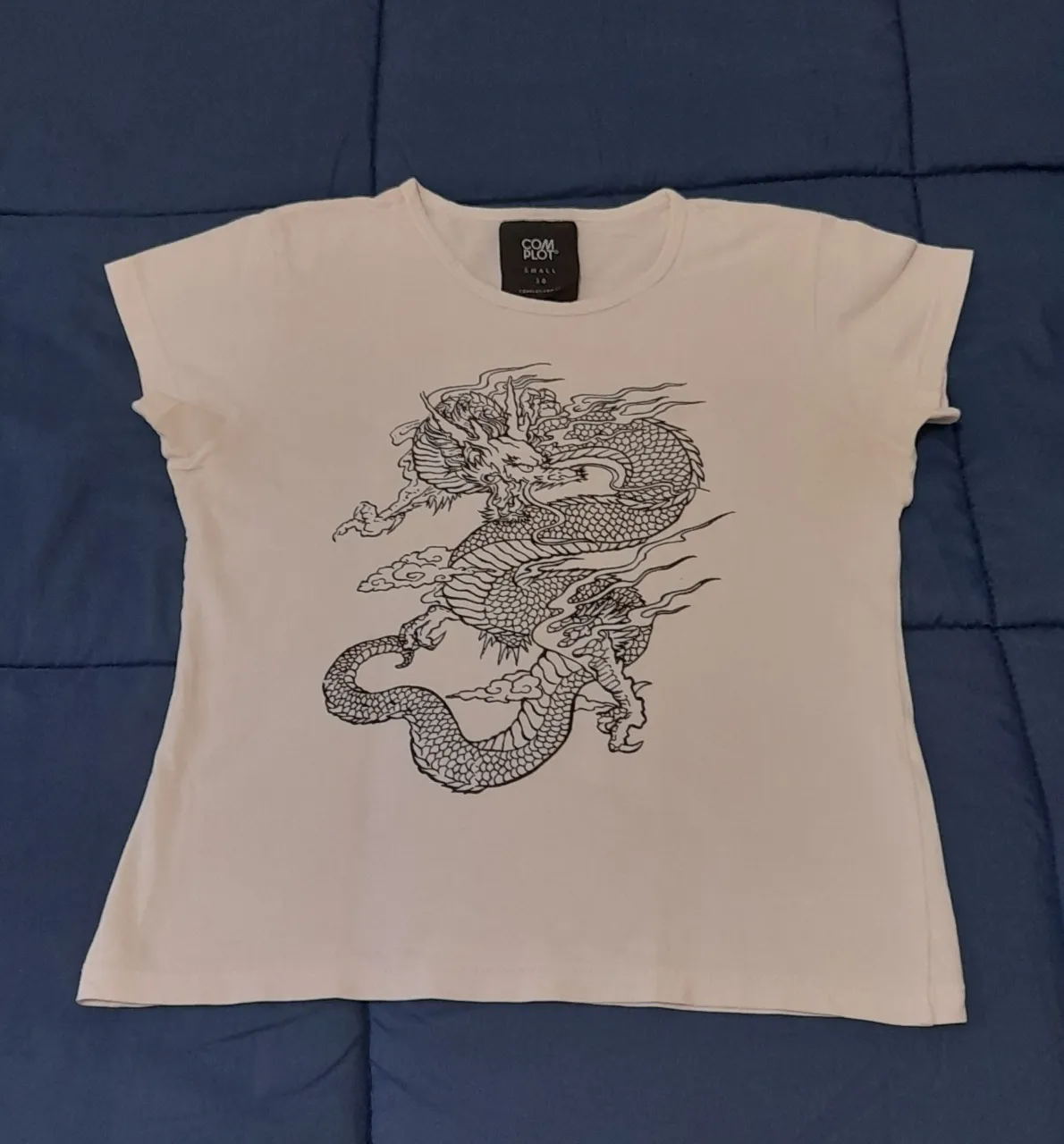 Remera blanca con estampa de dragón oriental en negro. Diseño único y llamativo, ideal para un look urbano y con onda.