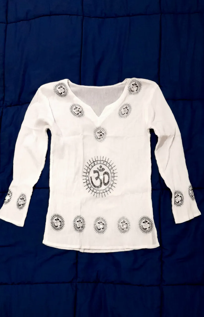 Camiseta blanca de bambula pura de india, lino de algodón. Manga larga con estampa de símbolo Om y detalles bordados en negro con espejitos. 
Posee cuello en V y aberturas laterales.
Original traída de India. 
Sin uso. Nueva. 

61cm de largo
45cm mangas 
38cm de axila a axila (51cm estirada)

