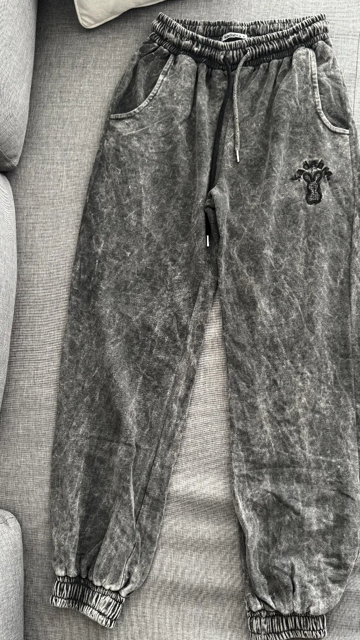 Pantalon de buzo gris con efecto desgastado y cordón. Ideal para un look urbano y cómodo.