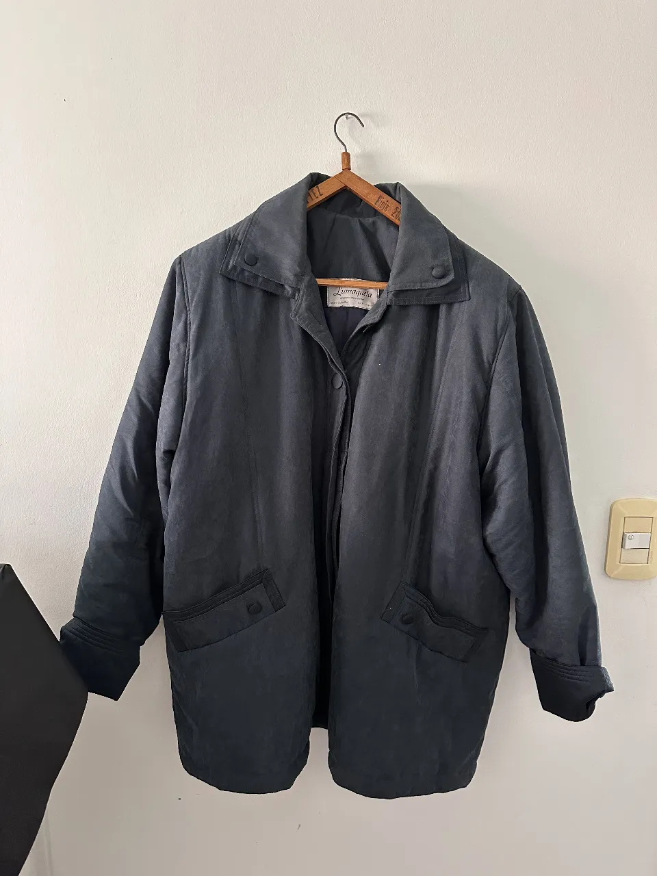 Campera bomber negra de tela tipo gabardina, con cuello solapa y bolsillos delanteros. Ideal para un look casual y abrigado.