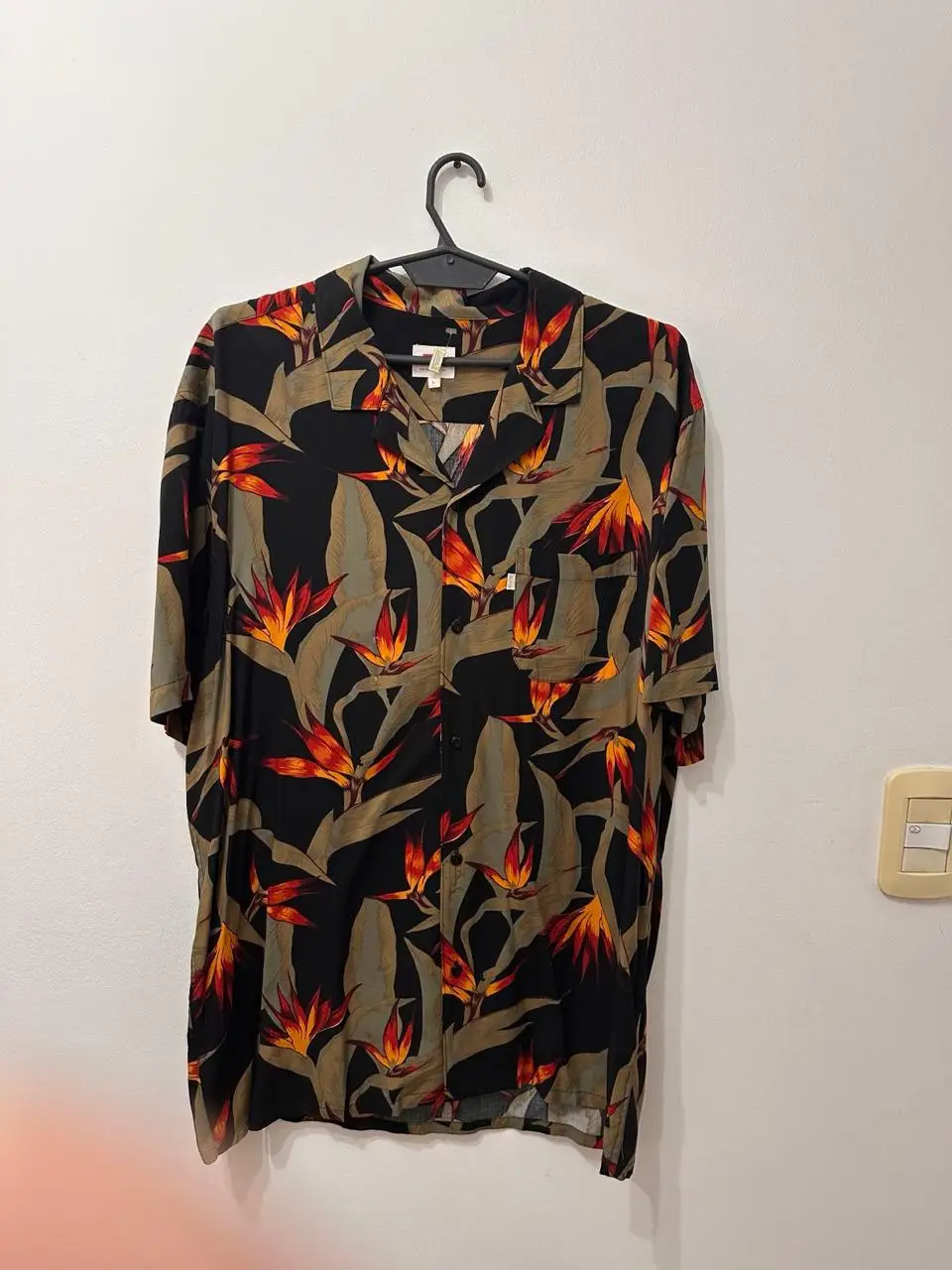 Camisa de hombre Levi's con estampado floral en tonos naranja, amarillo y marrón sobre fondo negro. Talle L. Ideal para un look casual y con onda.