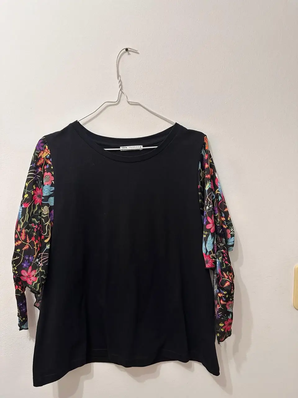 Blusa negra con mangas 3/4 estampadas con flores de colores. Ideal para un look casual y moderno.