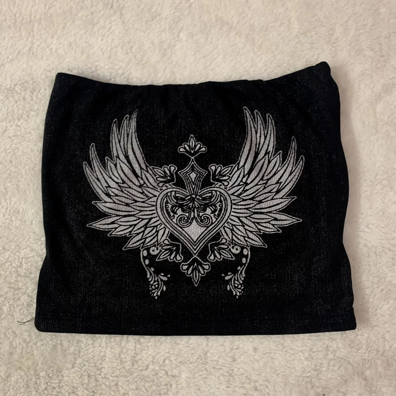 strappless top y2k 
Top negro con estampa de corazón alado y detalles ornamentales. Un diseño único y llamativo, perfecto para destacar tu estilo.