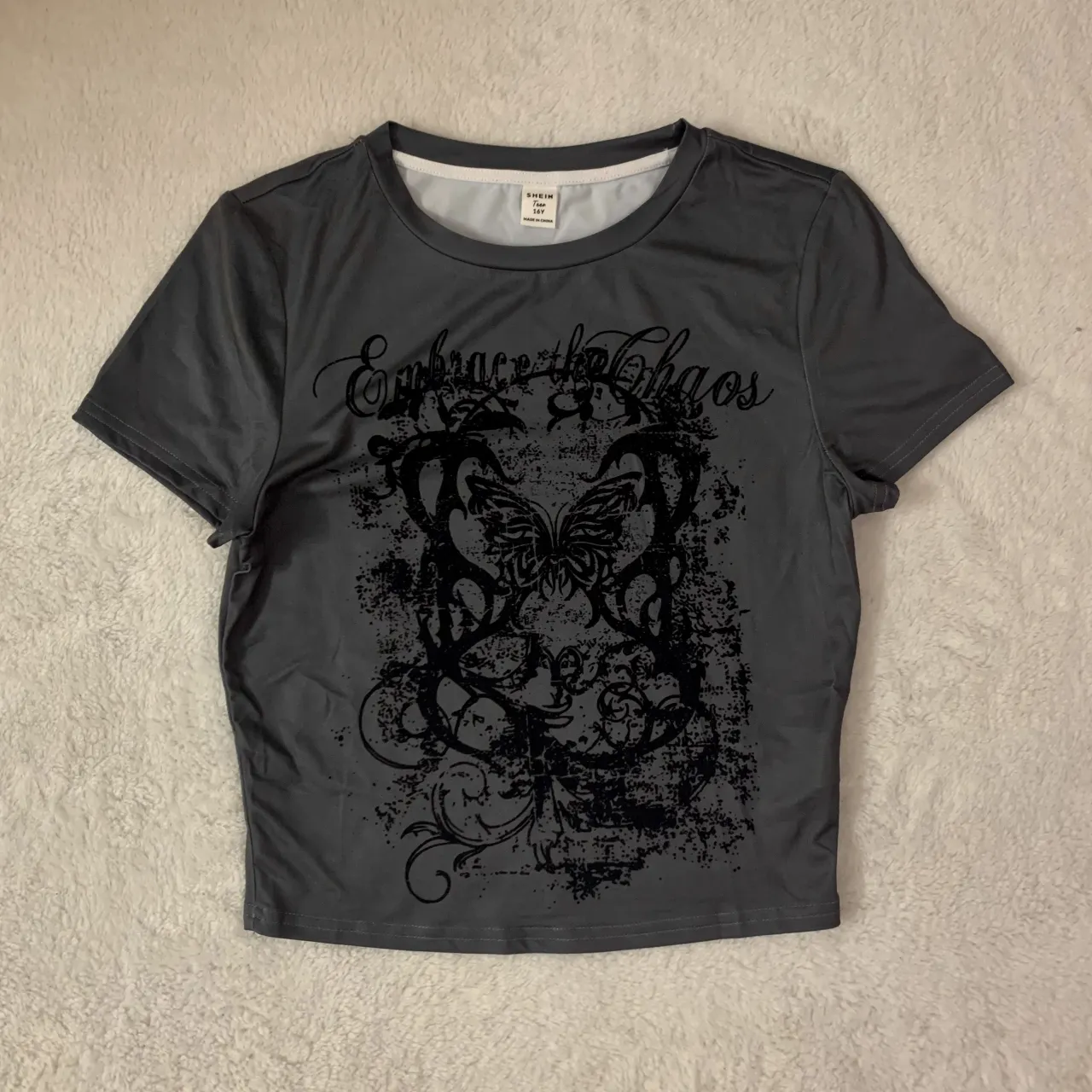 Baby tee shein nueva! 
Remera gris oscura con estampa "Embrace the Chaos" y mariposa. Diseño grunge y moderno, ideal para un look urbano y descontracturado.