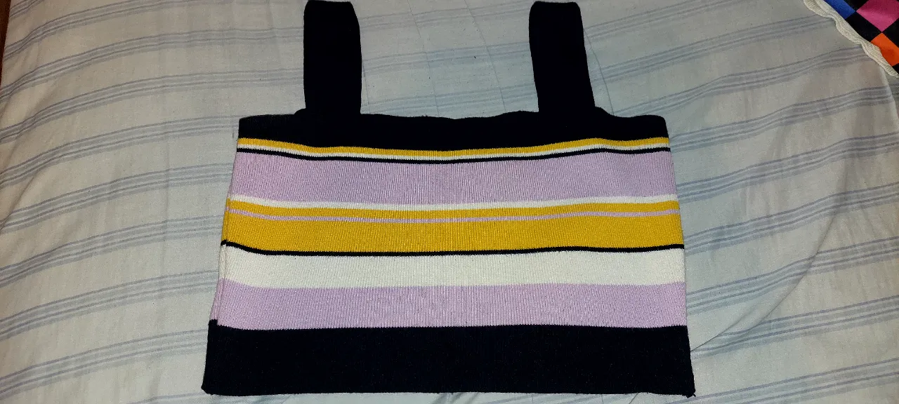 Top a rayas súper canchero, ideal para un look moderno y divertido. Combina colores vibrantes como el lila, amarillo y blanco sobre una base negra, con tiras anchas que le dan un toque único. Perfecto para el día o la noche.
