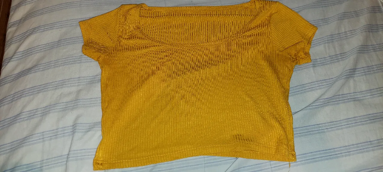 Remera amarilla de manga corta, con textura acanalada y escote cuadrado. Es una prenda corta y ajustada, ideal para un look casual y moderno.