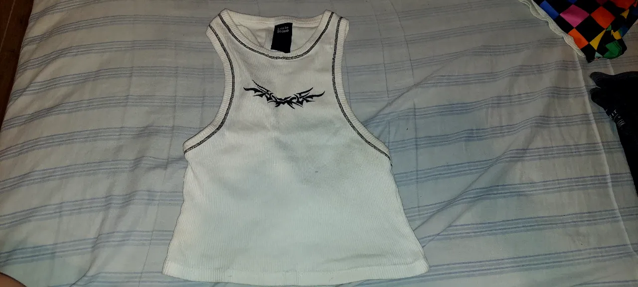 Top blanco de morley con estampa tribal y detalles de costura negra. Un básico canchero para armar looks modernos.