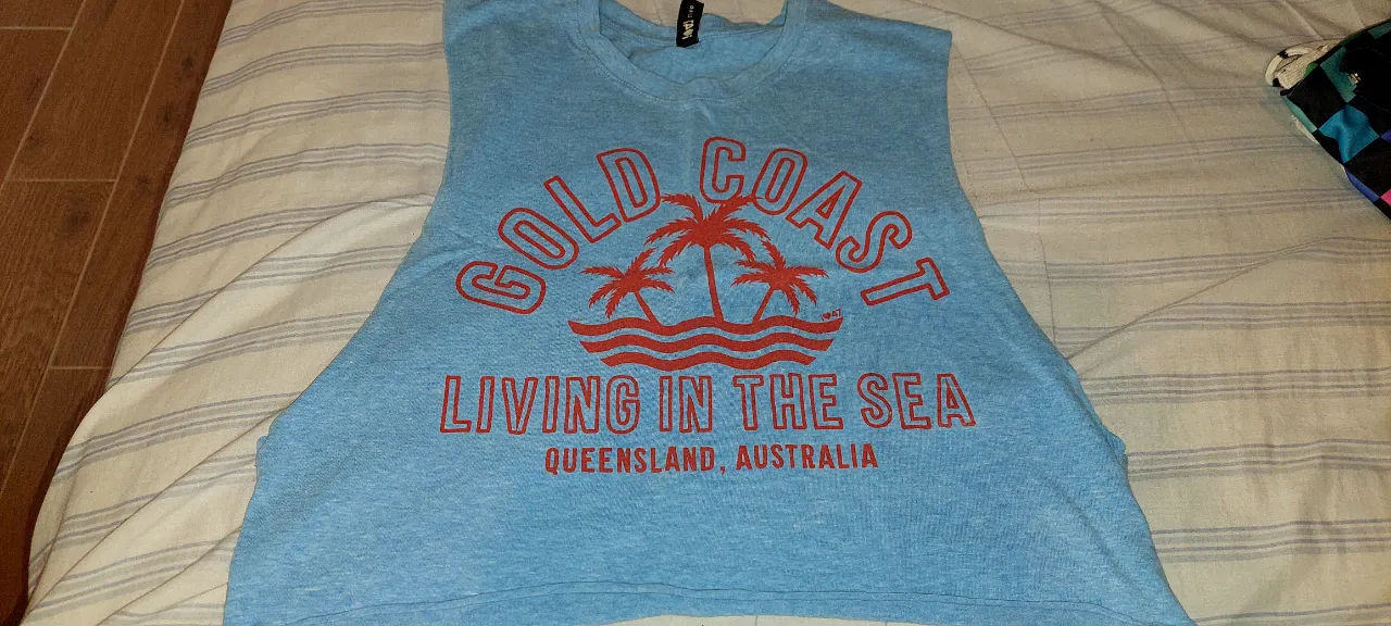 Musculosa súper canchera con estampa "Gold Coast" y palmeras. Ideal para un look relajado y playero. Perfecta para los días de sol y calor.
