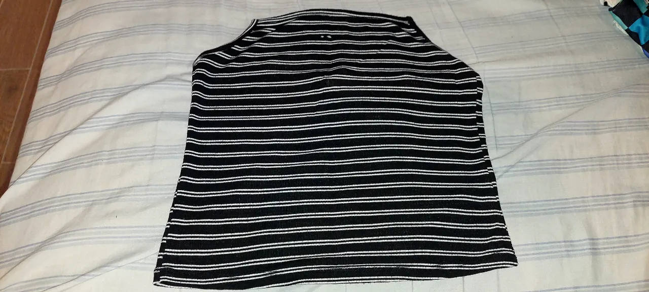 Remera a rayas blancas y negras, con dos pequeños agujeros en la parte frontal superior por el paso del tiempo.