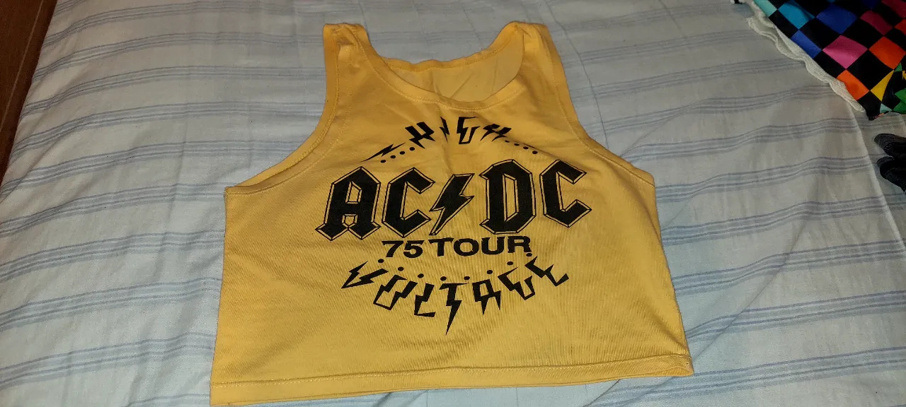 Musculosa amarilla de AC/DC, con estampa "HIGH VOLTAGE 75 TOUR". Ideal para fans del rock y para un look casual.