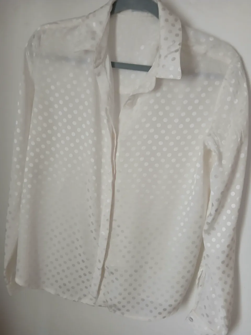 Camisa blanca con lunares blancos. Posee cuello camisero y botones al frente. Mangas largas con puño y botón. Talle SM 42