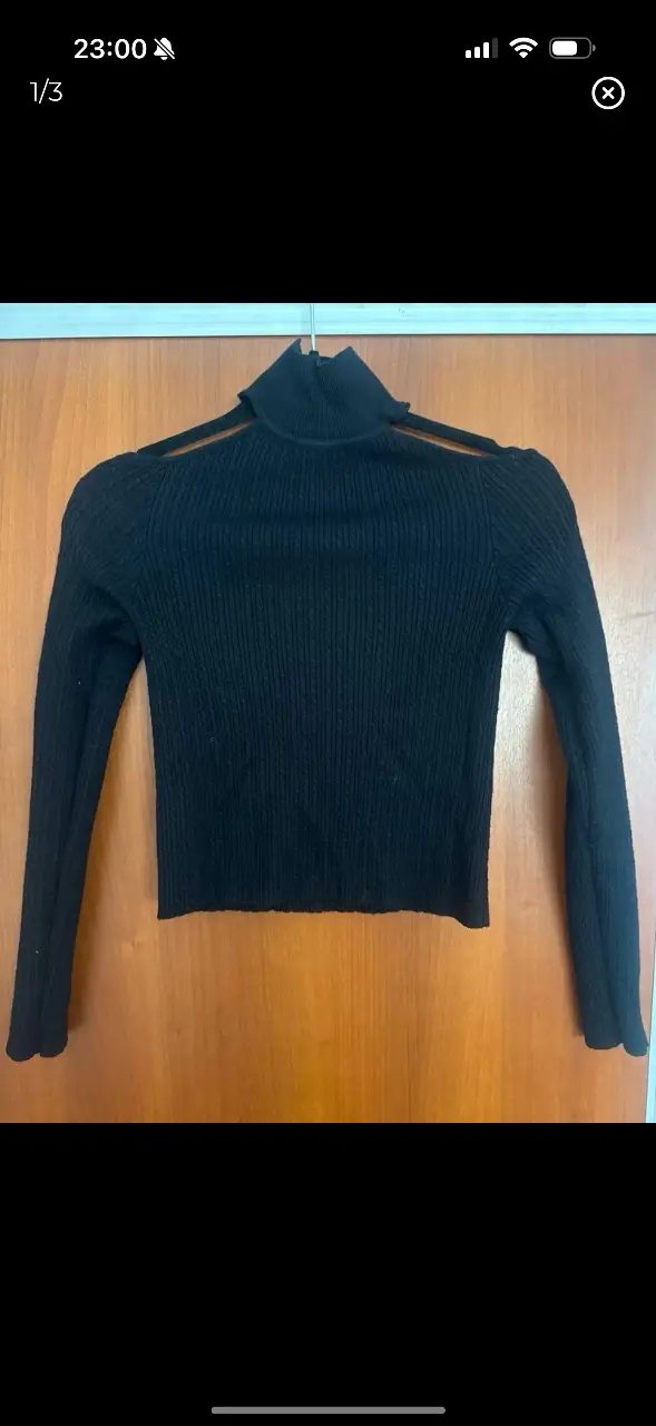 Remera manga larga negra con cuello alto y aberturas en los hombros. Ideal para un look moderno y sofisticado.