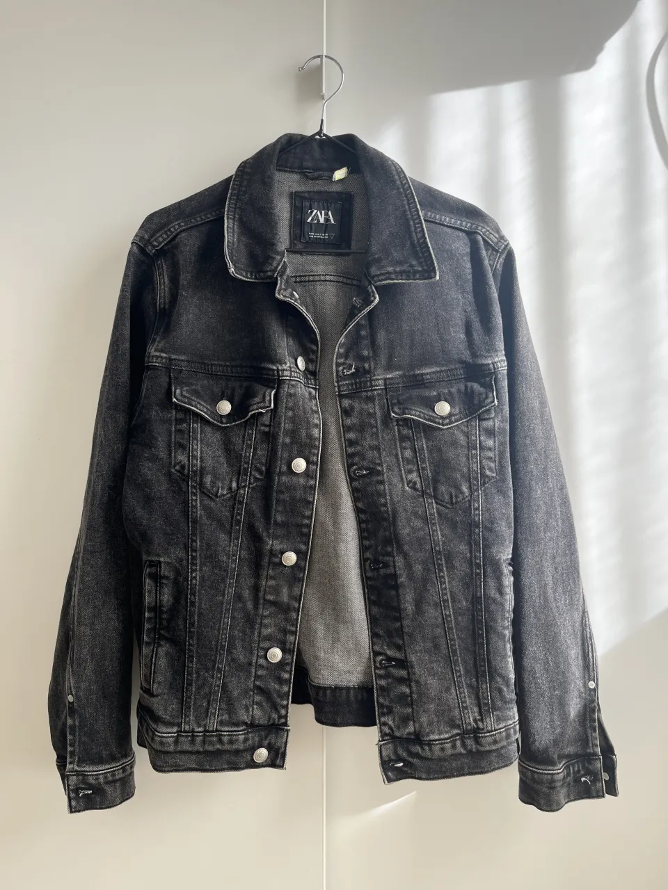 Campera de jean negra marca Zara, con botones metálicos y bolsillos frontales. Un clásico que no puede faltar en tu guardarropa.