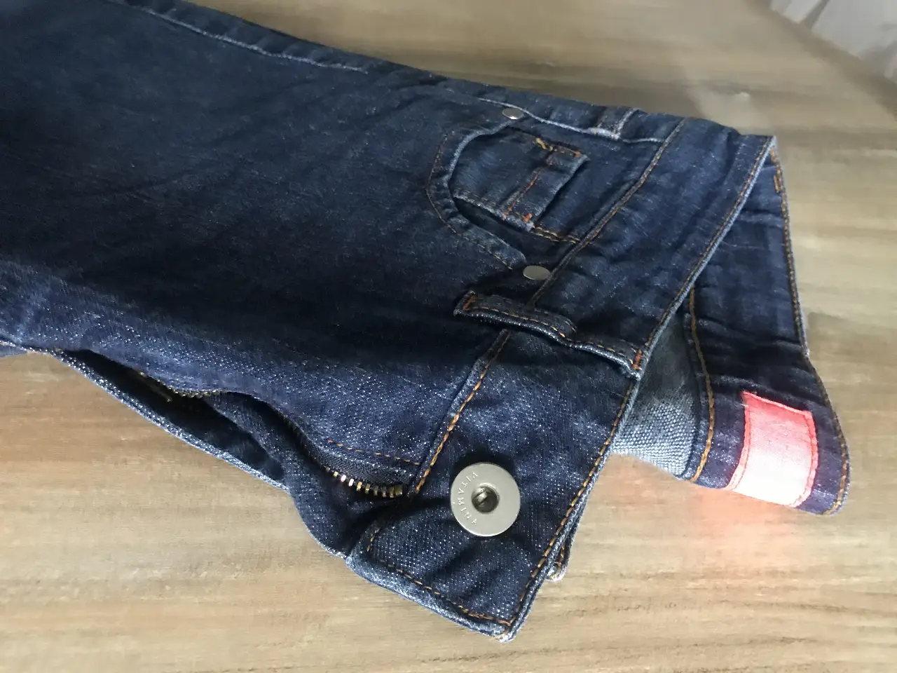 Jeans rectos de denim azul oscuro, con cierre y botón metálico. Posee detalles de costura en color ocre y etiqueta de la marca "Vitamina Jeans". Un clásico para cualquier ocasión.