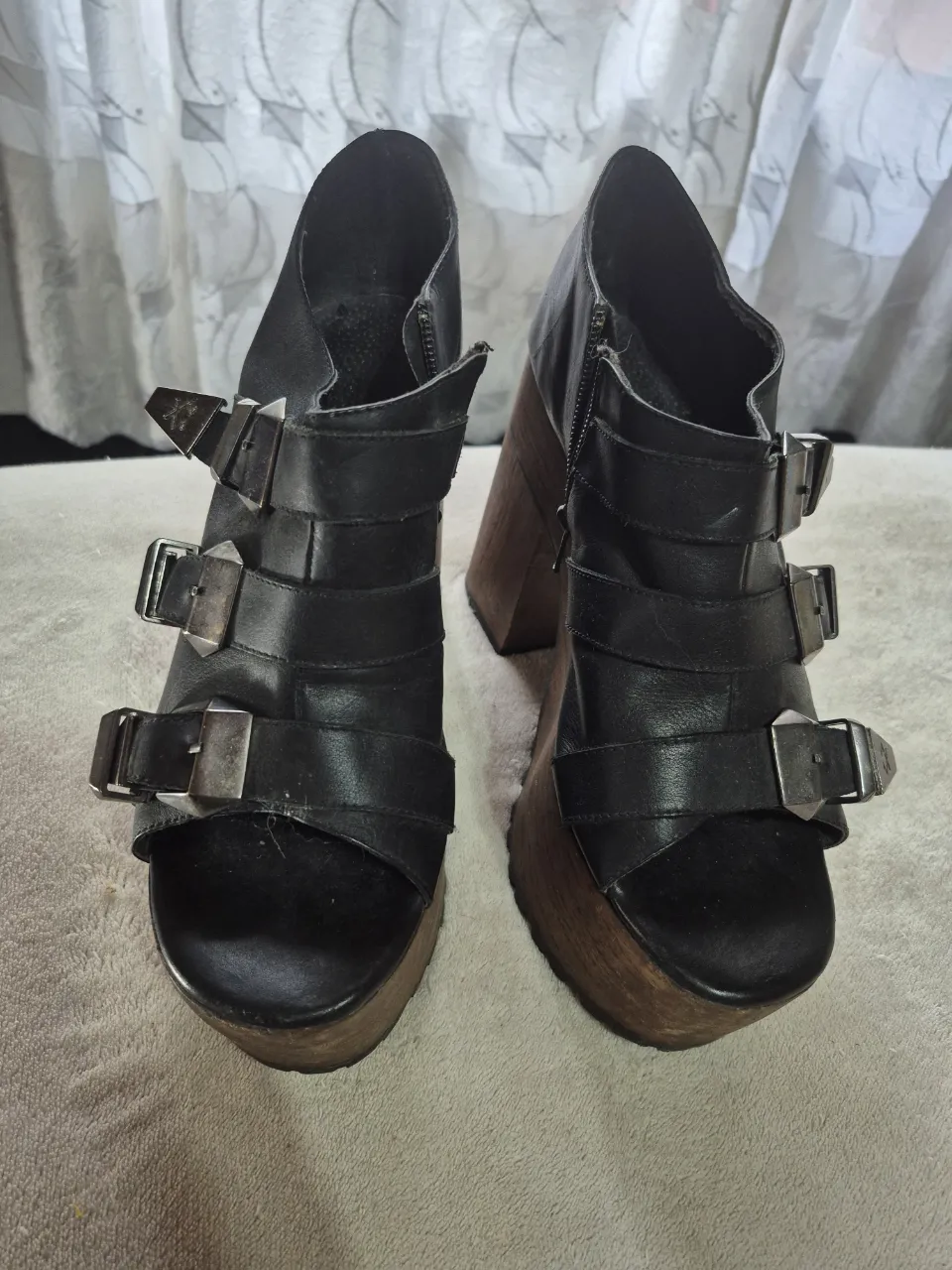 Botas de caña alta de cuero negro con detalles de hebillas plateadas y plataforma de madera. Estilo rocker y vintage.