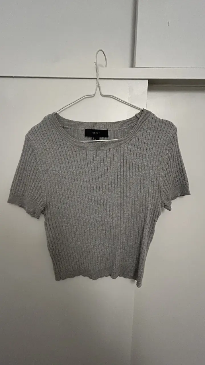 Crop top de tejido de punto acanalado, con cuello redondo y mangas cortas. Ideal para un look casual y moderno.