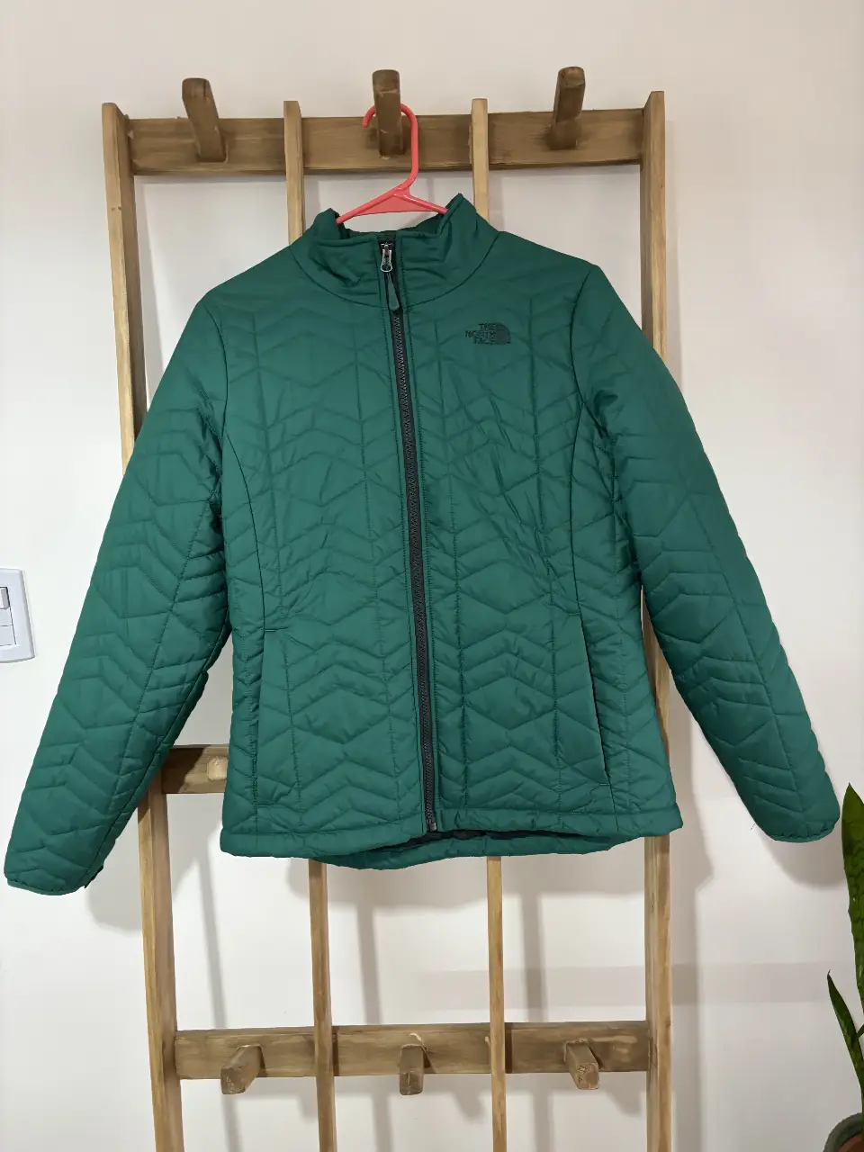 Campera The North Face verde, acolchada, con cierre y cuello alto. Ideal para el invierno.
