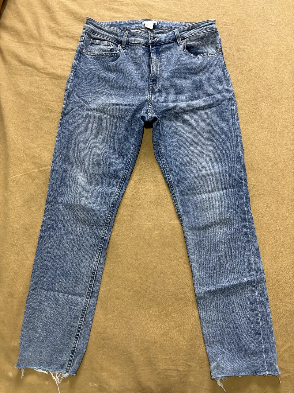 Jeans rectos de mujer, color azul claro, con detalles de desgaste y corte en el bajo. Talle 10.