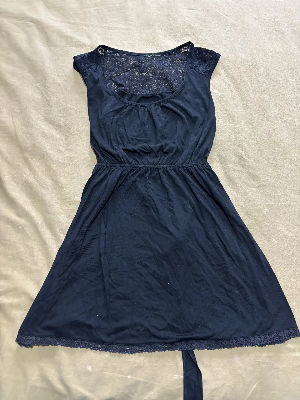 Vestido mini negro con detalles de encaje en la parte superior y en el borde inferior. Ideal para una salida casual o una fiesta.