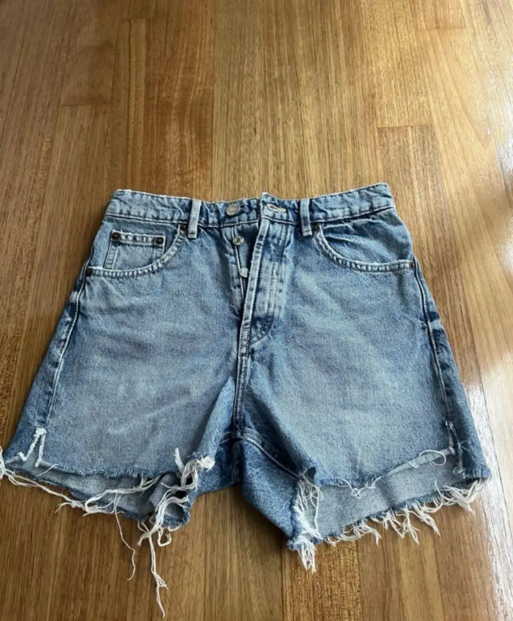 Short de jean de mujer, tiro medio, con detalles de roturas en los bordes. Ideal para un look casual y moderno.