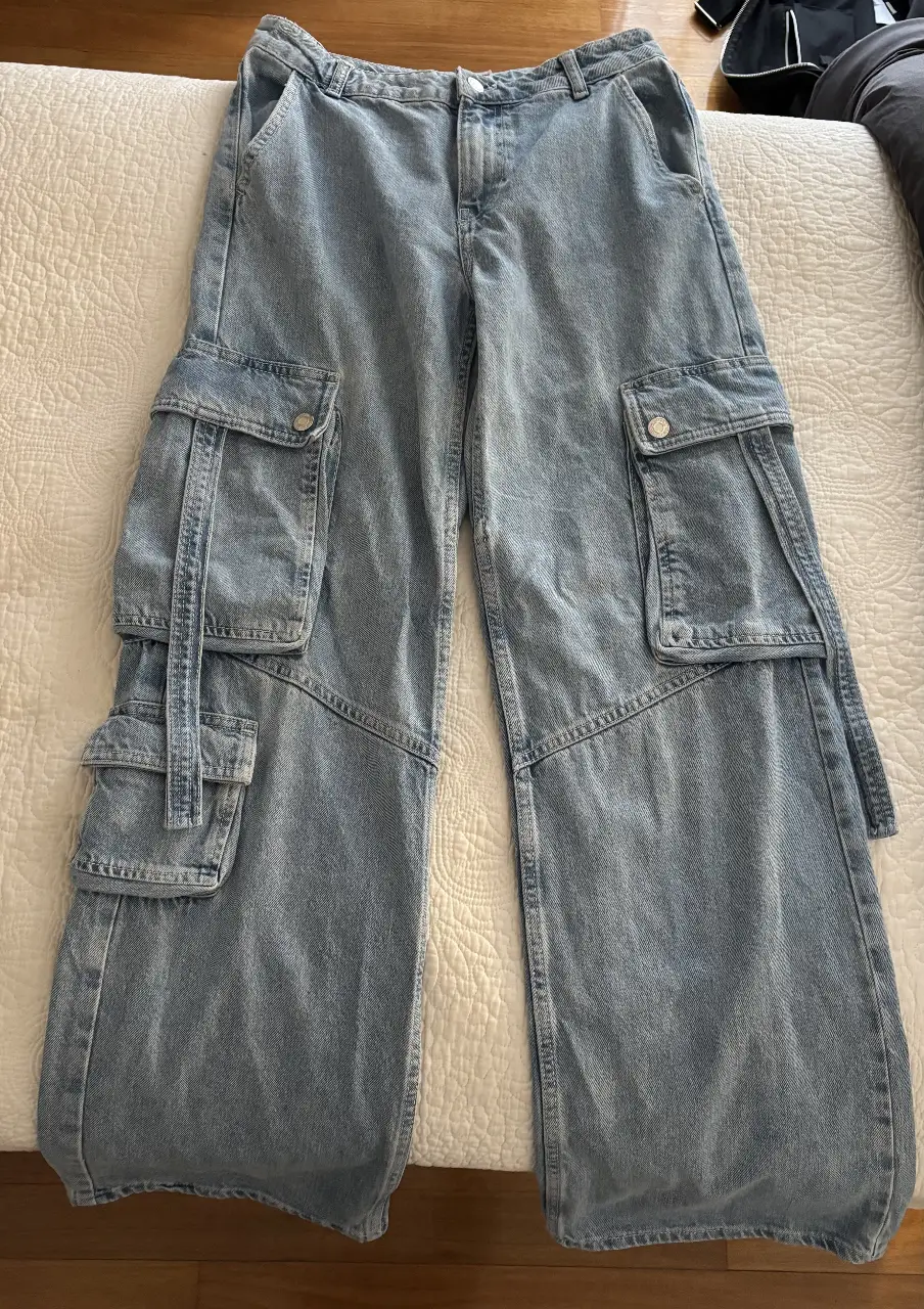 Pantalón cargo de jean celeste, tiro alto y corte ancho. Con bolsillos laterales amplios y detalles de costura. Ideal para un look casual y moderno.