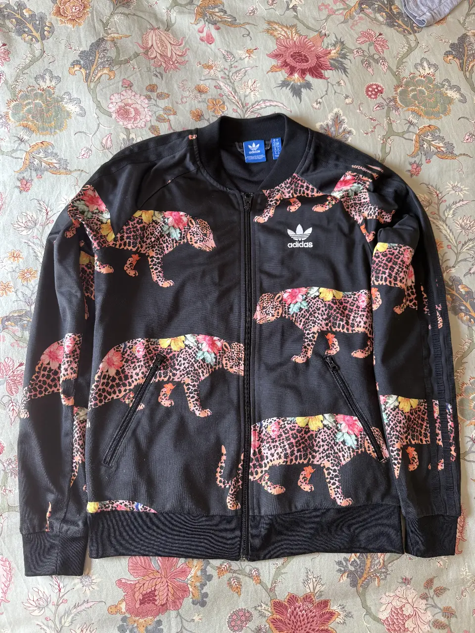 Campera Adidas Original negra con estampado de leopardo y flores. Con cierre y bolsillos. Talle S.