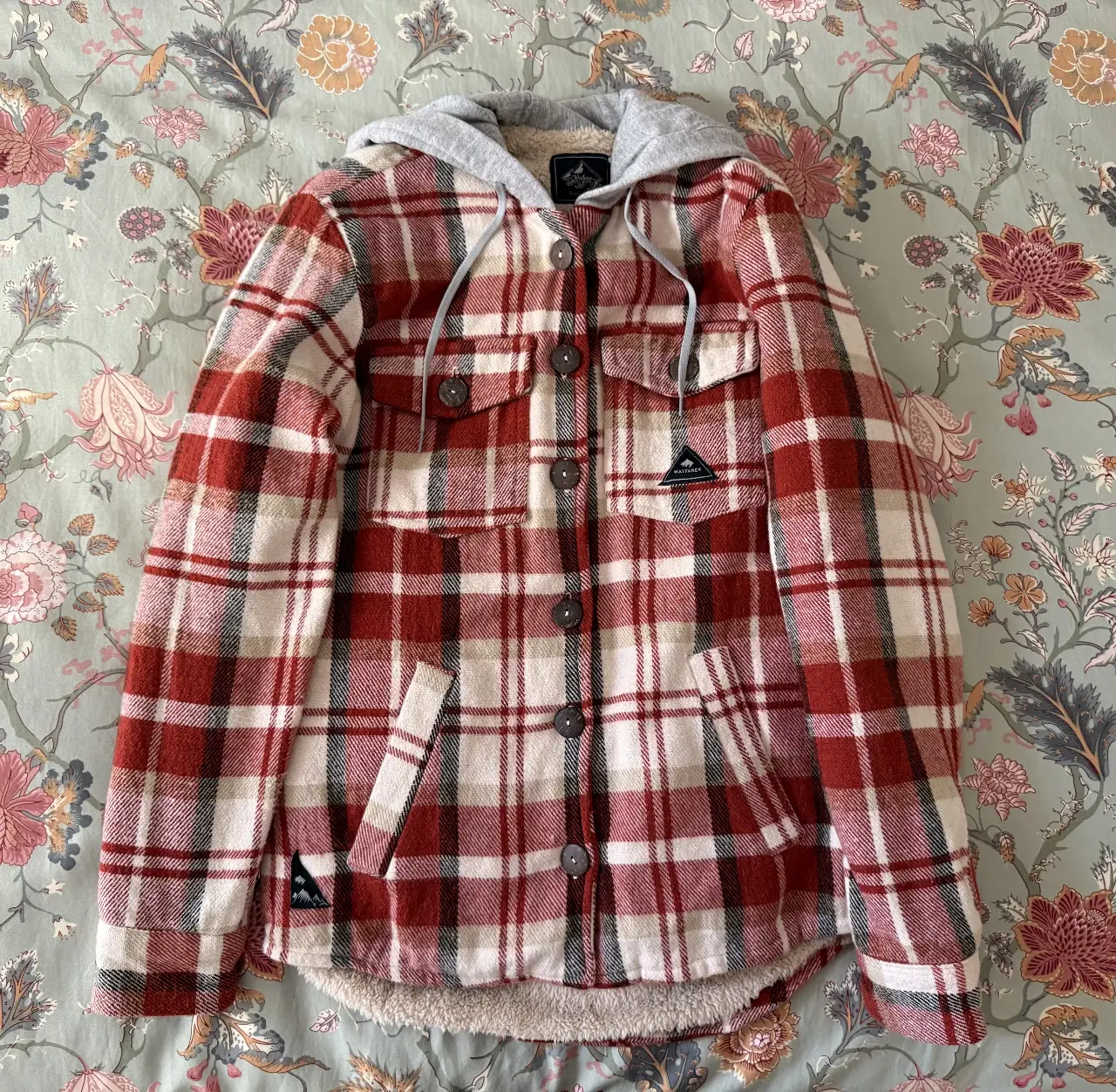 Impecable camisa de leñador a cuadros roja y blanca con capucha gris. Interior de sherpa para mayor abrigo. Ideal para el invierno.