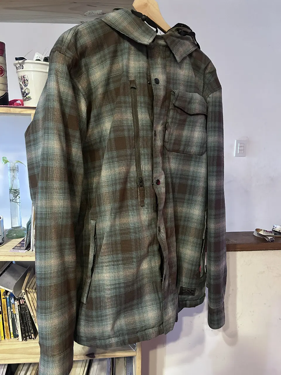 Campera de hombre 686 con capucha, de abrigo, con diseño a cuadros en tonos verdes y marrones. Posee cierre frontal, bolsillos y capucha con interior de piel sintética. Talle XL.