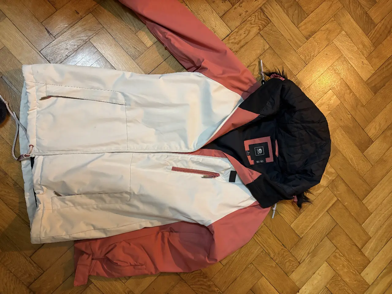 Campera de nieve para mujer, con diseño en blanco y rosa. Ideal para actividades de invierno y deportes de nieve. Cuenta con cierre frontal y capucha.