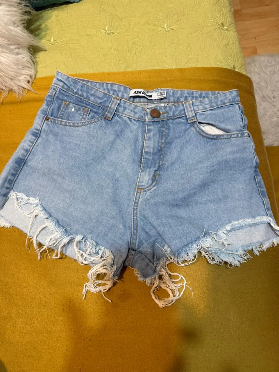 Shorts de jean tiro alto con roturas y flecos en el ruedo. Lavado celeste.