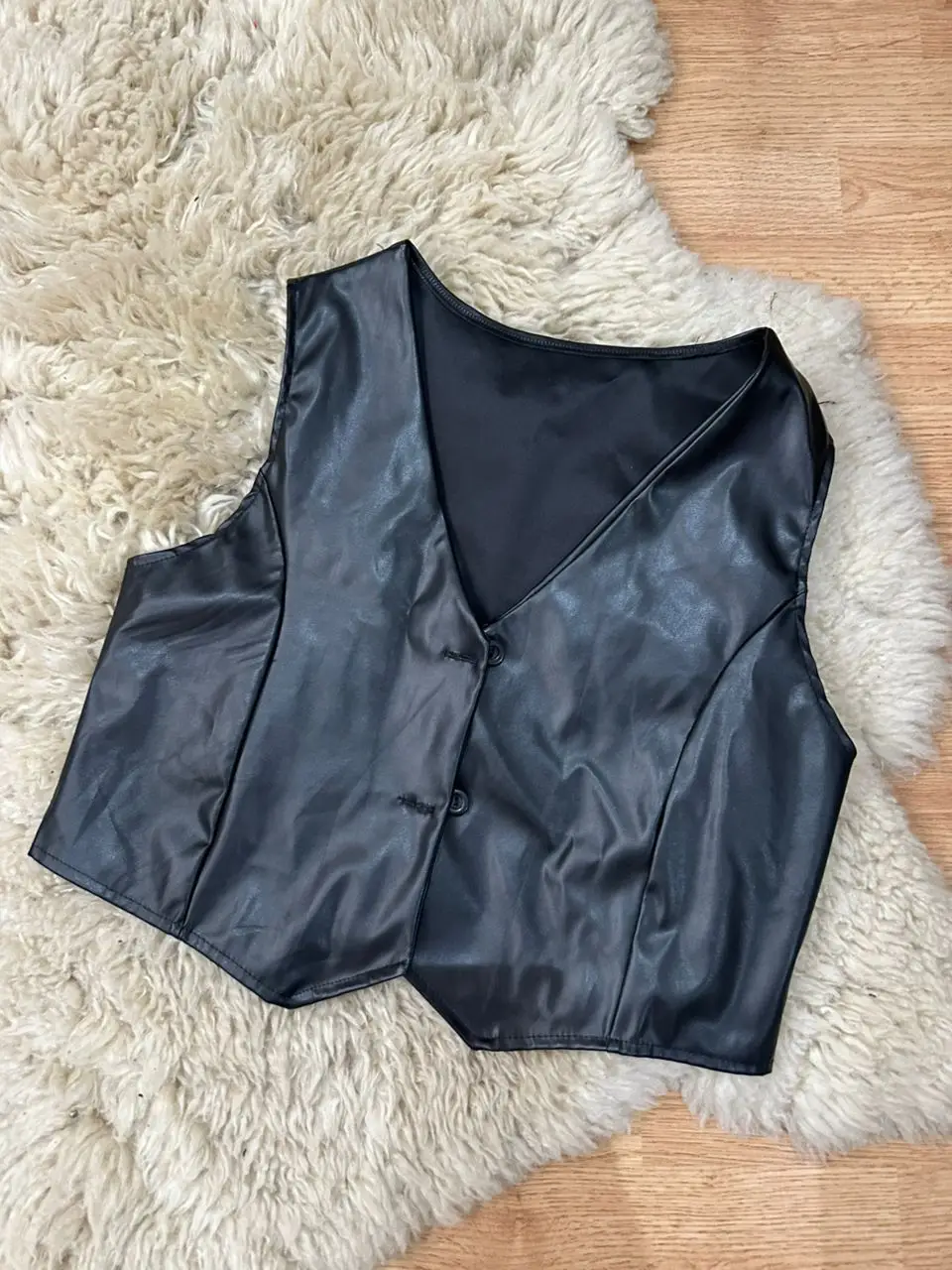 Chaleco de cuero sintético negro, con botones y corte entallado. Ideal para un look moderno y versátil.