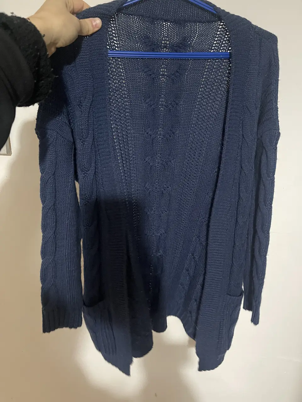 Cardigan de punto azul marino con diseño calado en la espalda y bolsillos. Ideal para un look casual y abrigado.