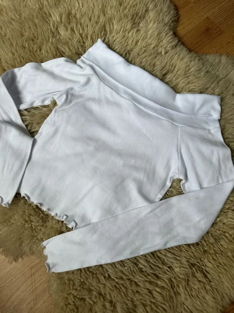 Remera manga larga blanca con cuello alto y detalle de volados en el borde. Ideal para un look casual y moderno.