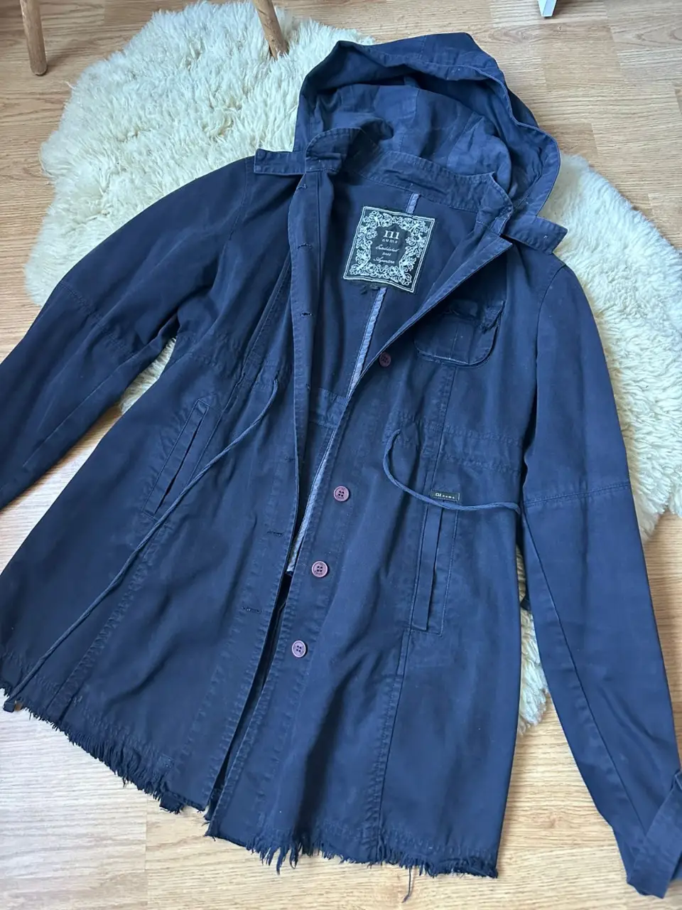 Campera azul con capucha, estilo utilitario, con detalles de botones y ajuste en la cintura. Ideal para un look casual y cómodo.