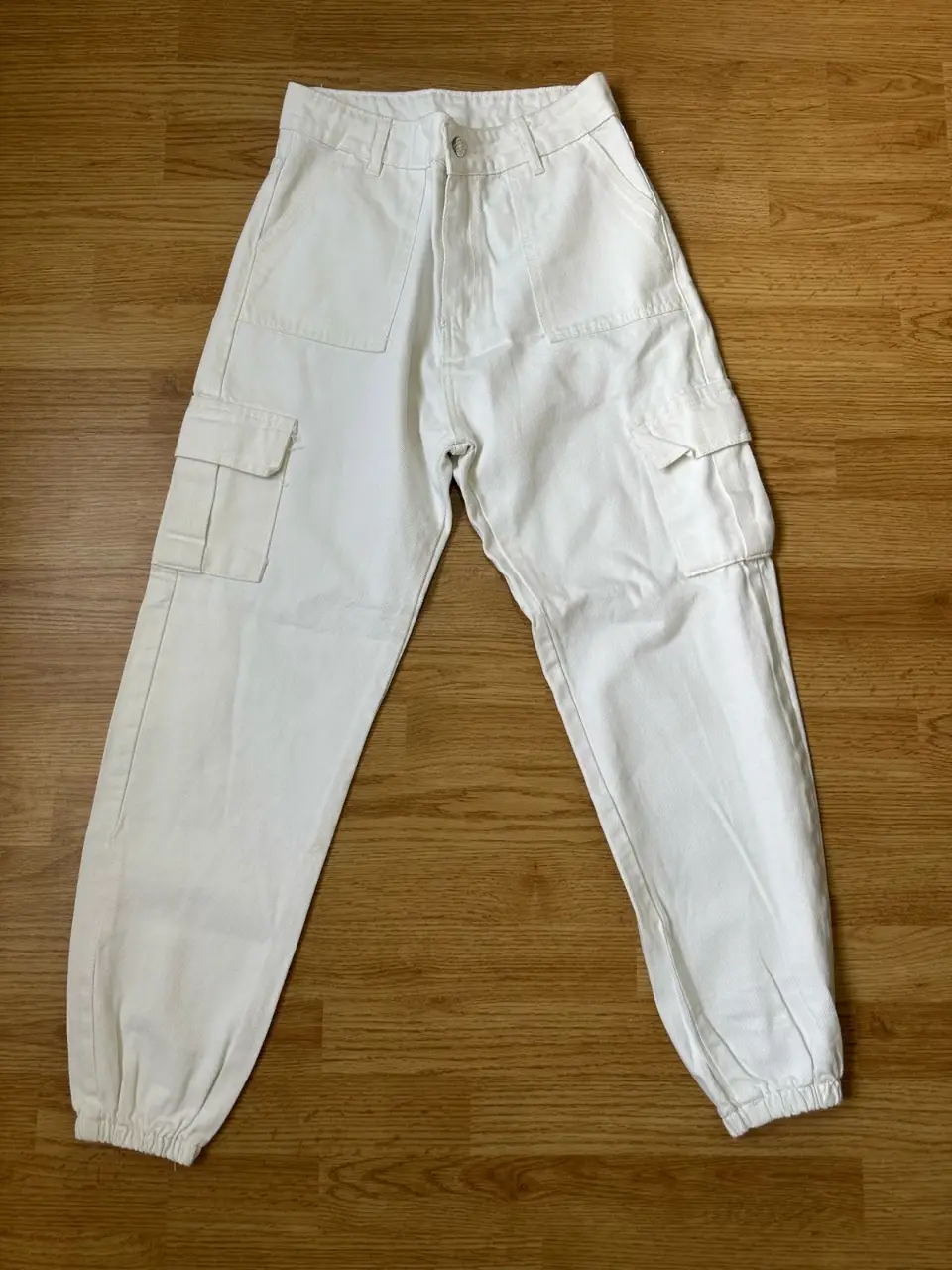 Pantalón cargo blanco, tiro alto, con bolsillos laterales y en la parte trasera. Ideal para un look casual y moderno.