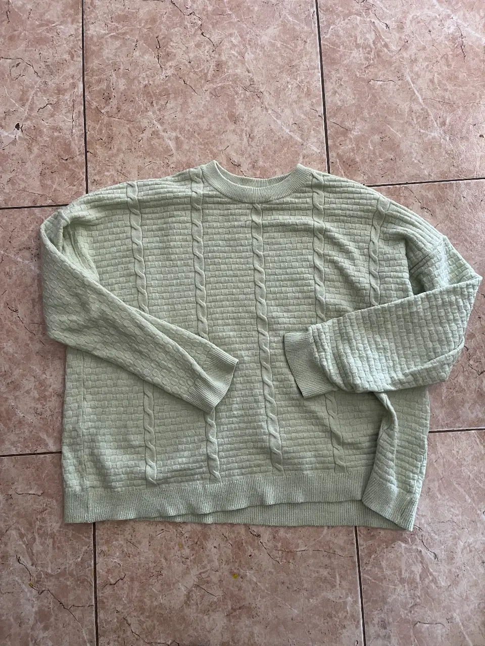Sweater de punto verde claro con diseño de trenzas. Ideal para un look casual y cómodo.