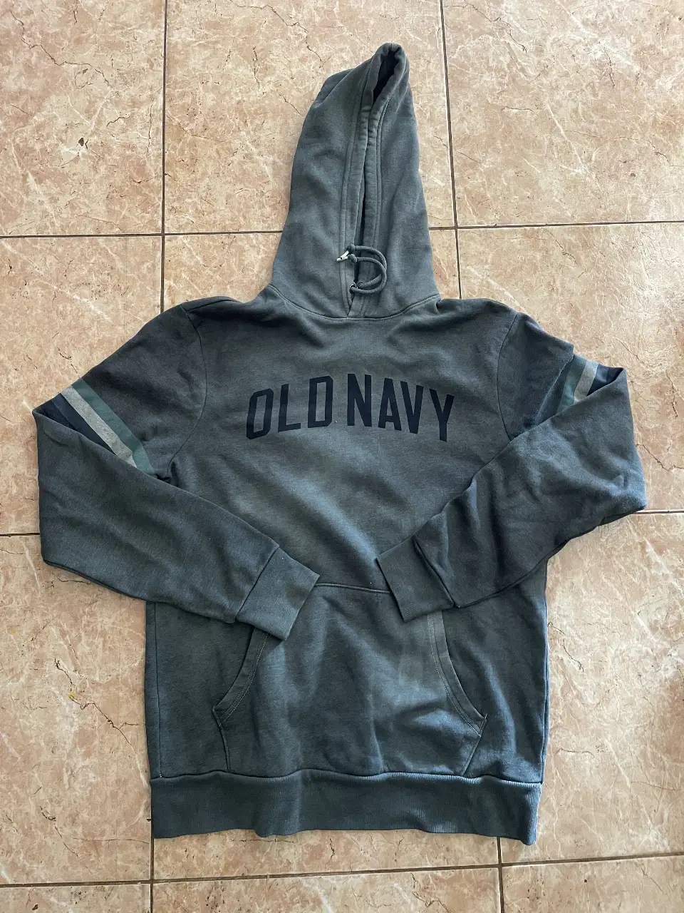 Buzo canguro Old Navy gris con capucha y bolsillo delantero. Detalles de rayas en las mangas.