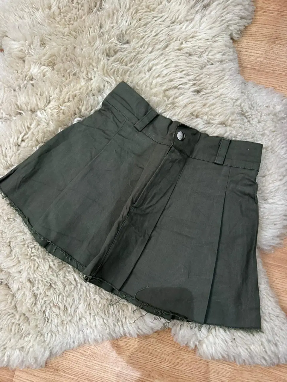 Minifalda verde oscuro con diseño plisado y detalles deshilachados en el borde. Ideal para un look casual y moderno.