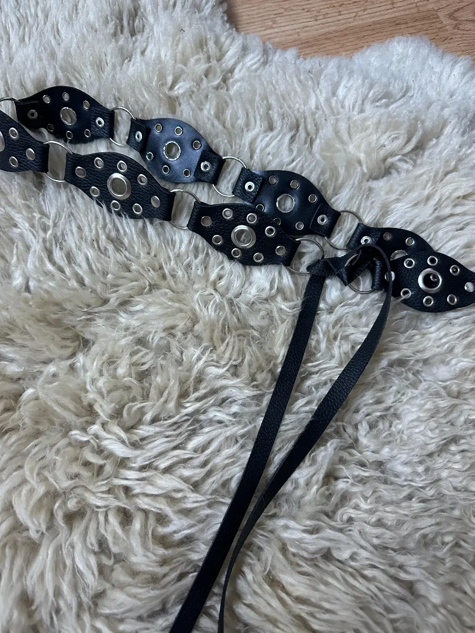 Cinturón de cuero negro con detalles de tachas y hebilla con forma de corazón. Ideal para darle un toque rockero a cualquier look.