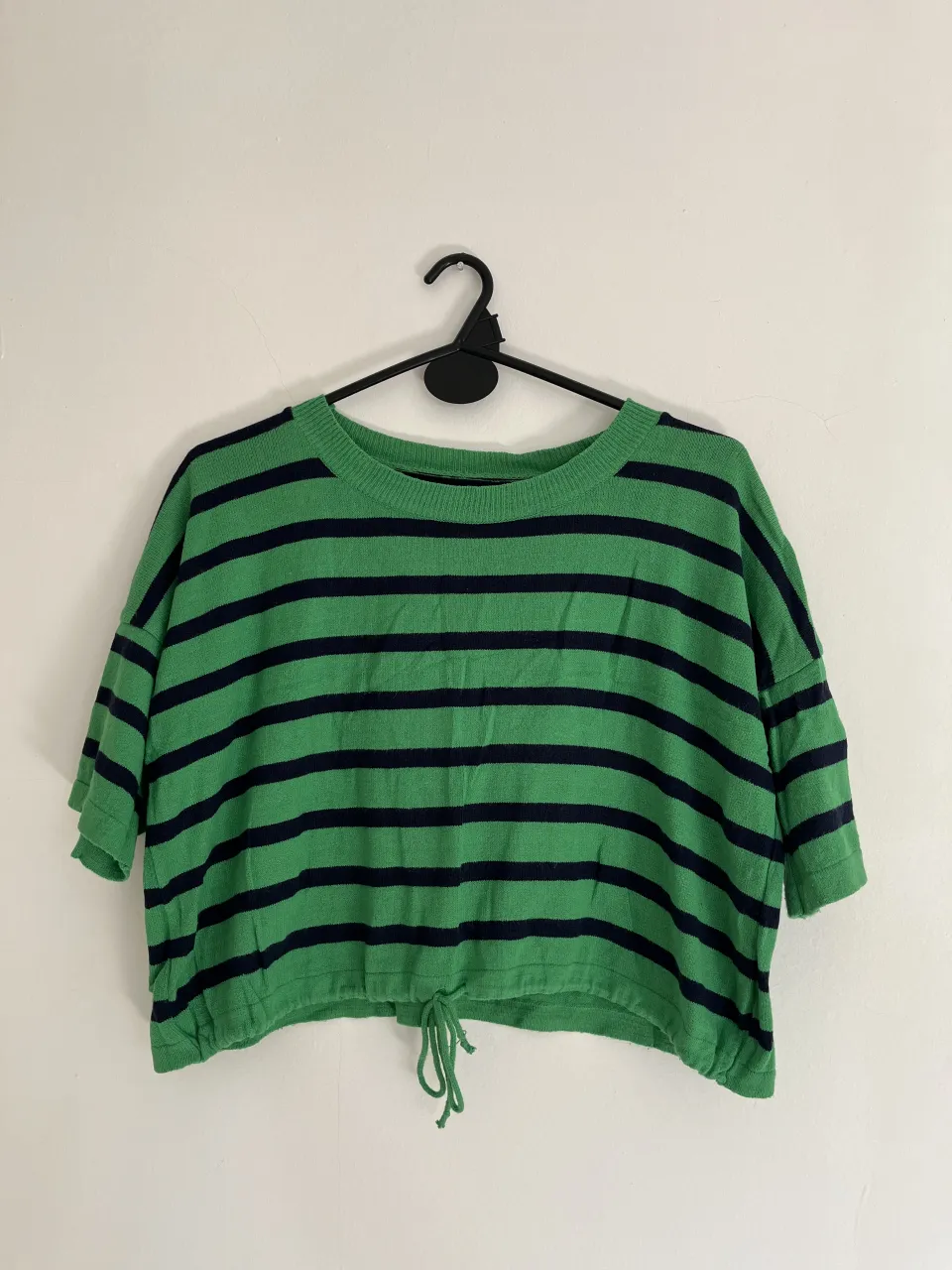 Remera a rayas verdes y azul marino, con cordón ajustable en la cintura. Manga corta y corte moderno.