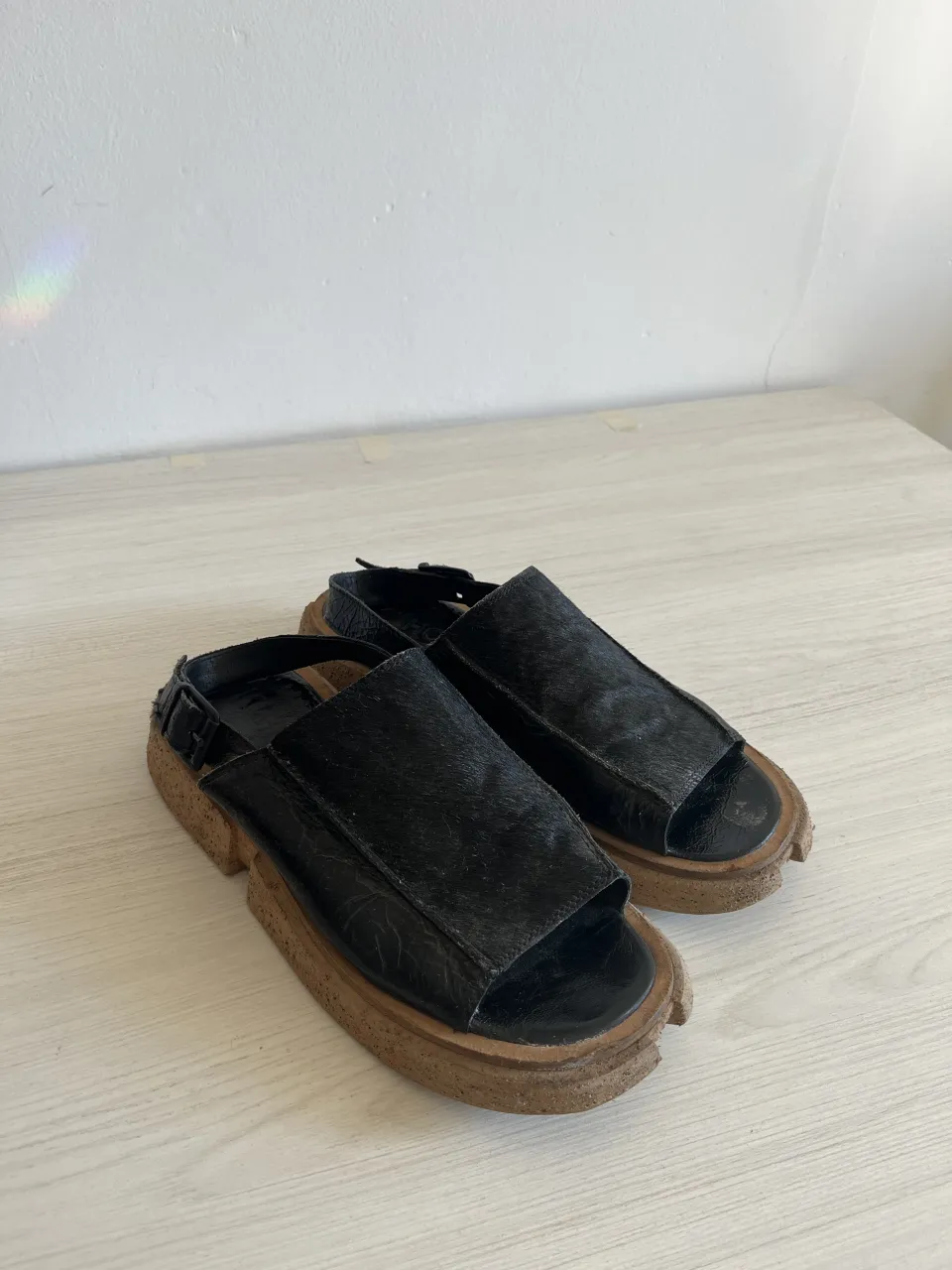 Sandalias negras de cuero con suela gruesa y diseño moderno. Perfectas para un look casual y vanguardista.