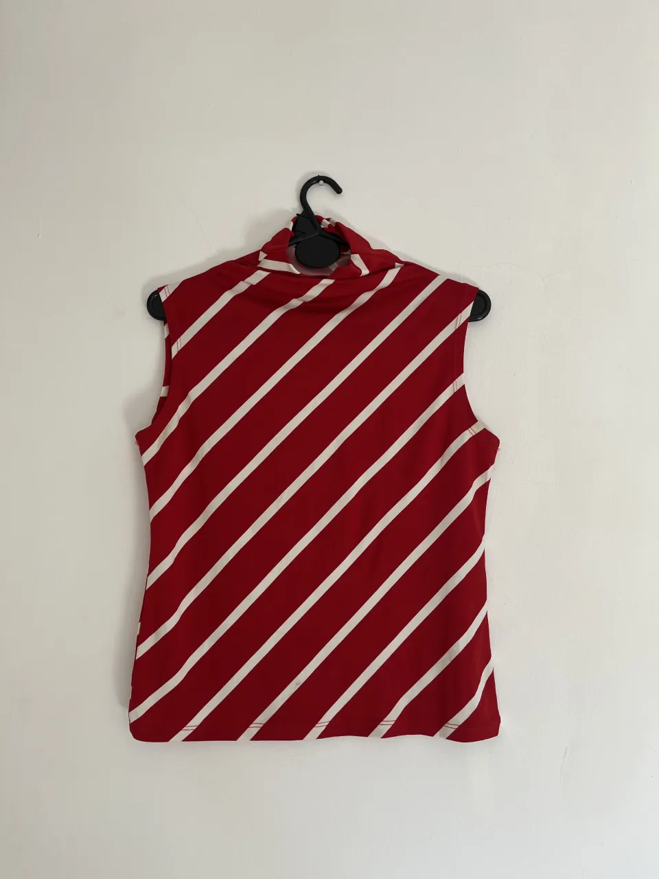 Remera sin mangas a rayas rojas y blancas, con cuello alto. Ideal para un look casual y canchero.
