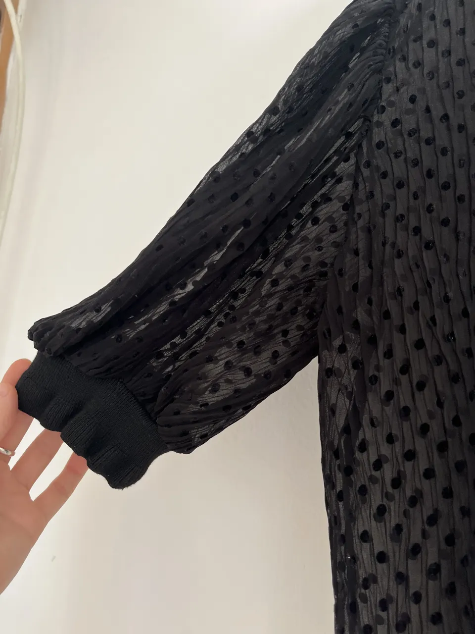 Blusa negra con lunares transparentes y mangas abullonadas. Un diseño delicado y con un toque romántico, ideal para lucir en una salida o una fiesta.